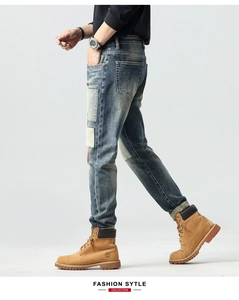 Detail of vintage blue slim fit jeans with patch splice design and washed denim texture