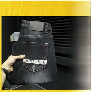 Détail du jean noir pour homme avec ruban lettré blanc sur la poche arrière