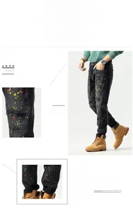 Detail of slim-fit men's black ripped jeans featuring artistic multicolor paint splatter