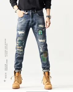 Detail of blue patchwork denim jeans with distressed holes and embroidered patches