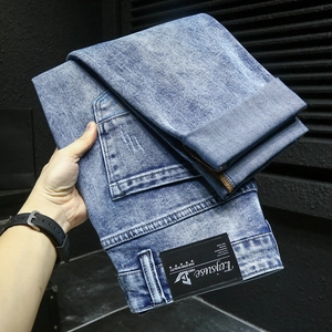 Détail d'un jean délavé bleu clair montrant l'étiquette en cuir vintage et la texture denim