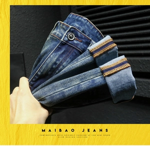Close-up of deep blue denim jeans showing orange contrast stitching and metal button detail
