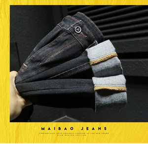 Vue détaillée du denim noir avec coutures contrastées orange et bouton métallique robuste