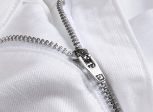 Close-up of durable silver metal zipper and stitching on white denim jeans