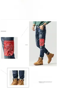Detail von blauen Destroyed-Jeans mit roten Bandana-Patches und weißen Farbspritzereffekten