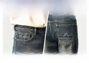 Detailed view of blue wavy embroidery on the pockets of vintage washed men's denim jeans