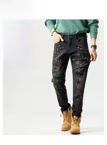 Detail shot of men's distressed black slim jeans with colorful street style paint splashes