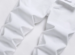 Detailed close-up of white slim fit jeans featuring zipper fly and durable stitching