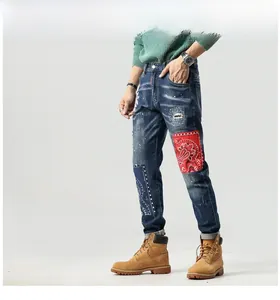 Detail der Ripped Jeans mit rotem Paisley-Patchwork und blauer Musterbestickung