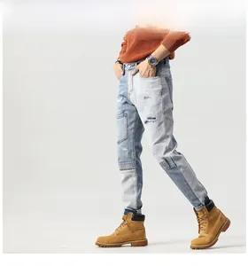Detail view of men's patchwork denim jeans with distressed holes and street style embroidery