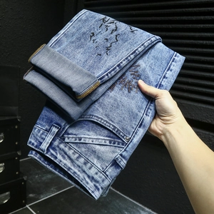 Détail du denim délavé bleu avec imprimé graffiti et broderie en zigzag jaune