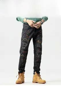 Detail of slim fit black jeans with distressed ripped holes and colorful paint splatter