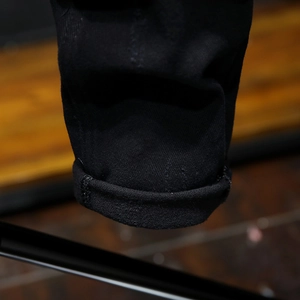 Men's slim fit black distressed jeans featuring ribbed hem and warm fleece lining detail