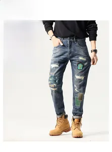 Close-up of patchwork embroidery and distressed details on men's streetwear denim jeans