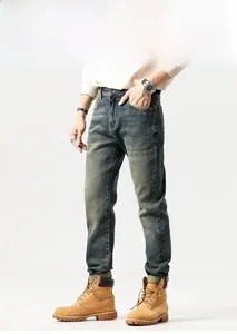 Detail of vintage washed slim fit denim jeans with retro whiskers and work boots