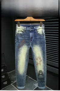 Detail of slim-fit blue jeans with yellow-green wash and orange rhinestone lightning decor