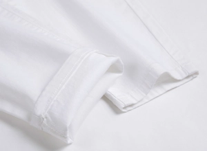 Detailed macro view of pure white twill cotton pants hem showing clean stitching lines