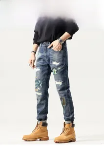 Detail shot of distressed blue jeans featuring patchwork embroidery and vintage washed denim