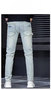 Detail of light blue patched slim fit denim jeans with white embroidery on back waist
