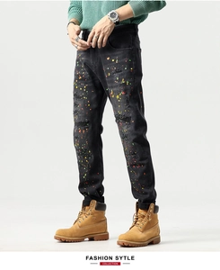 Detailed macro view of colorful paint splatter and distress marks on men's black denim jeans