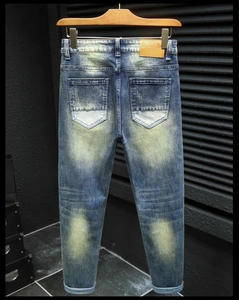 Detailed view of men's slim fit jeans with vintage acid wash and brown leather patch