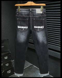 Détail de jean noir slim avec imprimés sur les poches arrière et texture denim délavée