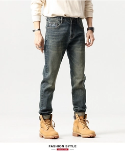 Detail of dark blue washed denim jeans showing embroidered pocket and faded cat whisker effect