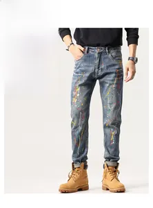 Détail du jean slim bleu pour hommes avec des taches de peinture multicolores artistiques