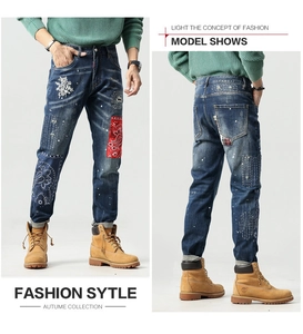 Vintage blaue Jeans mit floraler Stickerei, Bandana-Patches und weißen Farbspritzern im Detail