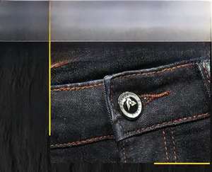 Détail d'un jean denim foncé avec coutures orange contrastées et bouton en métal