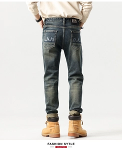 Close-up of vintage washed blue denim jeans featuring leather patch and wavy back pocket stitching