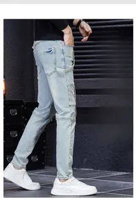 Detail of slim straight light blue cargo jeans with ripped patches and decorative straps