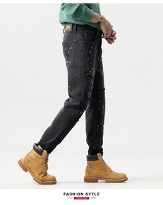 Detail of slim-fit black jeans with multicolor paint splashes and distressed ripped effects