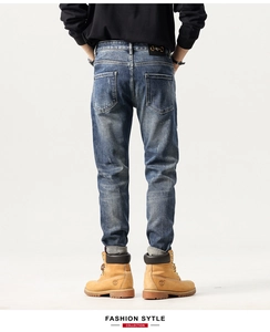 Detail view of denim jeans back with black leather patch and gold horsebit hardware