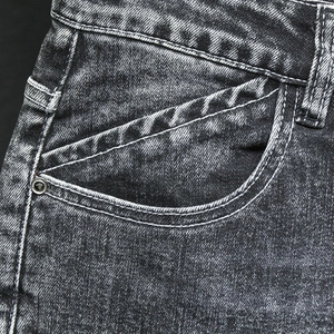 Détail du denim noir délavé avec texture vintage et rivets métalliques renforcés
