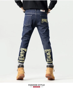 Détail de broderie jaune sur les poches arrière d'un jean bleu foncé ajusté pour homme