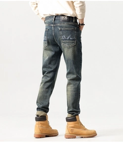 Detailed view of dark blue washed jeans showing back pockets with blue letter embroidery