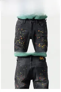 Detailed view of black slim-fit jeans with artistic colorful paint splatters and SA leather patch