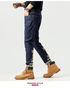 Détail d'un jean bleu foncé avec impression de lettres jaunes et motifs street style