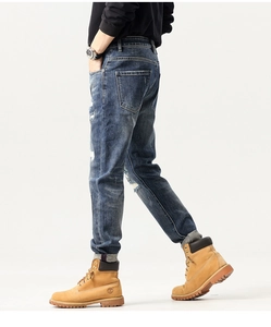 Detail view of men's distressed slim fit blue jeans with patchwork and embroidery accents