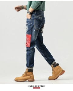 Detailaufnahme der Slim-Fit-Jeans mit Paisley-Aufnähern und weißen Farbspritzern