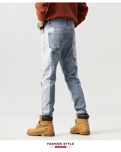 Detail view of men's slim fit jeans with unique blue patchwork design and wash finish