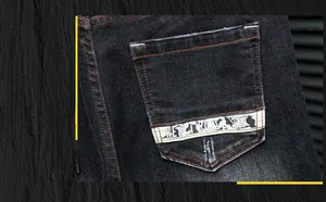 Vue détaillée d'un jean en denim noir avec coutures orange et ruban décoratif sur la poche arrière