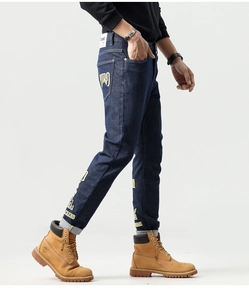 Détail du jean bleu foncé avec des imprimés graphiques jaunes VIRO et LEGEND stylisés