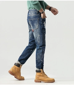 Detail der schmalen Jeans mit Patchwork-Stickerei, Distressed-Löchern und Farbspritzern