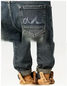 Detail of vintage washed blue jeans with curve embroidery on pocket and folded cuffs
