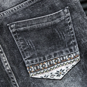 Détail de la poche arrière du jean délavé avec broderie de motif ethnique coloré