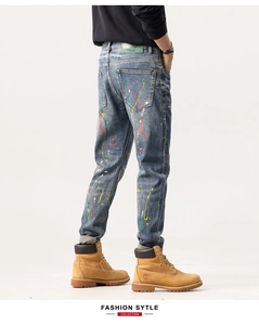 Détail d'un jean slim pour homme avec taches de peinture colorées et étiquette premium