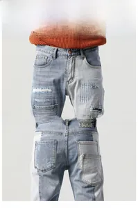 Detailed macro view of light blue distressed patchwork denim with embroidery and pocket accents