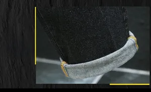Vue détaillée du revers de jambe avec couture surjetée colorée sur un jean en denim